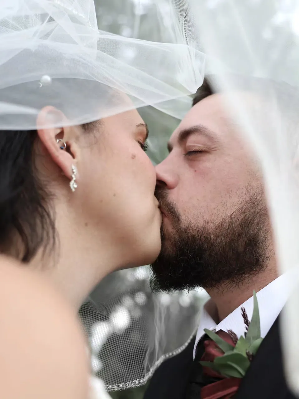A bride and groom kissing beneath her veil